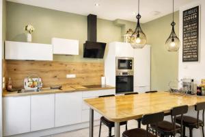 a kitchen with white cabinets and a wooden table at Au jardin de la Basilique in Boulogne-sur-Mer