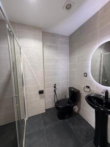 a bathroom with a black toilet and a sink at Résidence Soavina in Antananarivo