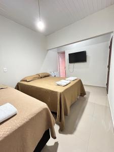 two beds in a room with a tv on the wall at Pousada Morada Nobre in Barreirinhas