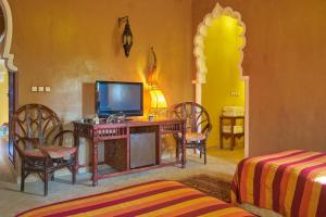 a room with a desk with a television and chairs at Hotel Kasbah Azalay in Mhamid