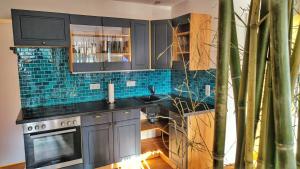 a kitchen with black cabinets and blue tile on the wall at AMORE 69 bei Greta in Marl