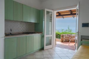 a kitchen with green cabinets and a view of a patio at Hotel Villaggio Cala Di Volpe in Capo Vaticano