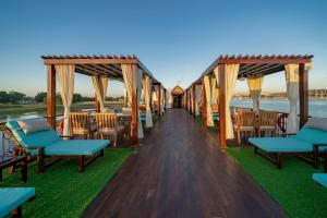a dock with chairs and tables on the water at Princess Farida Luxury Dahabiya Nile Cruise, Every Monday from Luxor to Aswan 4 nights and Every Friday from Aswan to Luxor 3 nights in Luxor