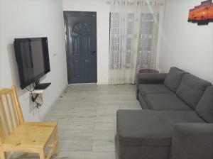a living room with a couch and a tv and a door at LBranco in Porto Novo
