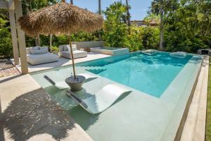 a swimming pool with a straw umbrella and a chair at Luxury 5BR Villa with Pool Jacuzzi 2 Golf Carts in Punta Mita