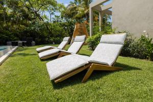 four lounge chairs sitting on the grass next to a pool at Luxury 5BR Villa with Pool Jacuzzi 2 Golf Carts in Punta Mita