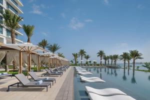 a row of chairs and umbrellas next to a swimming pool at ADDRESS RESIDENCES BEACH RESORT BAHRAiN in Rayyā
