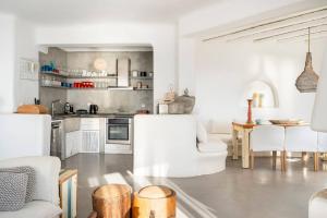 a white kitchen with white chairs and a table at Boutique Villa Aquata Private pool in Mikonos