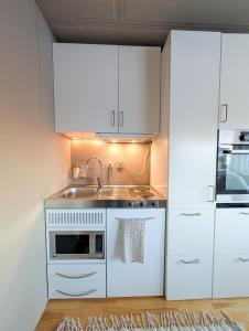 a kitchen with white cabinets and a sink and a microwave at Private Studio with Bathroom and Kitchen, Central Location in Tromsø +2 photos