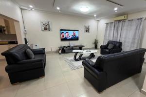 a living room with two black chairs and a tv at Artem Apartments - Apartment 2 in Kitwe