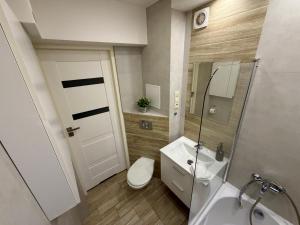 a bathroom with a white toilet and a sink at Apartament w centrum Konina in Konin