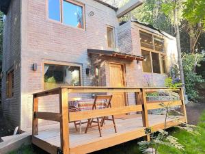 a deck with chairs and a table in front of a house at Tranquila y moderna en el bosque in San Carlos de Bariloche