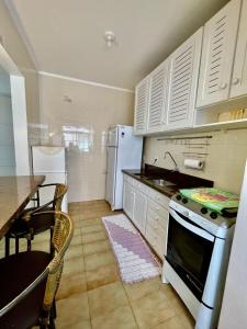 a kitchen with white cabinets and a table and a refrigerator at Apto 1 dormi in Capão da Canoa