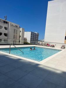 a swimming pool on a building with two people in it at NEW Apartment, Sea Front & Shared Pool in Quarteira