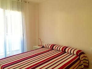 a bedroom with a striped bed with a window at Apartment in Estartit with garden in L'Estartit