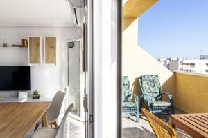a living room with a balcony with chairs and a table at Penthouse Pink seafront in La Mata +36 photos