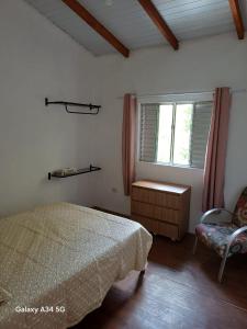 a bedroom with a bed and a chair and a window at Mar e descanso in São Sebastião