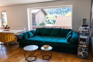 a living room with a blue couch and a large window at Gemütliches Gästezimmer mit gemeinsamer Küche, Wohnzimmer & Balkon in Nassereith