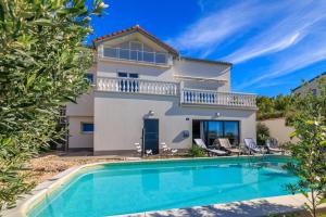a villa with a swimming pool in front of a house at Villa The Sunset View in Nehaj