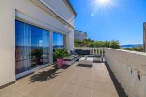 a balcony with a couch and chairs on a house at Villa The Sunset View in Nehaj