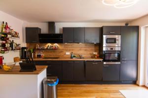 a kitchen with black cabinets and stainless steel appliances at Gemütliches Gästezimmer mit gemeinsamer Küche, Wohnzimmer & Balkon in Nassereith