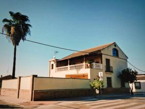 a white building with a balcony and a palm tree at Chalet in Rivero de Posadas with Pool in Rivero de Posadas