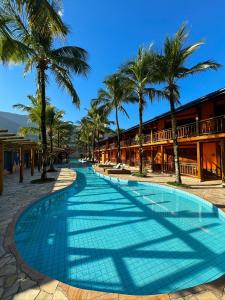 a swimming pool in front of a resort with palm trees at Hotel Pousada Tambayba in Maresias