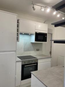 a kitchen with white cabinets and a microwave at Luxury 2-Bed Apartment with Parking & Garden in Borehamwood