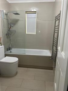 a bathroom with a tub and a toilet and a window at Luxury 2-Bed Apartment with Parking & Garden in Borehamwood