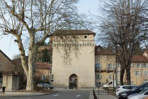 a building with a clock tower on the side of a street at Charmant studio - Centre historique de Crémieu in Crémieu