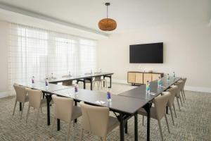 a conference room with tables and chairs and a flat screen tv at SpringHill Suites by Marriott Jacksonville Beach Oceanfront in Jacksonville Beach