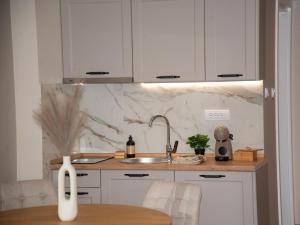 a kitchen with white cabinets and a sink and a table at PANTEX Centar Zlatibor in Zlatibor