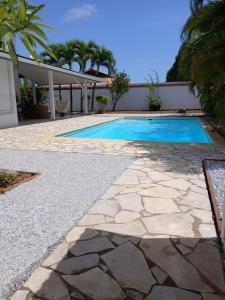 a swimming pool with a stone walkway next to a house at LE ROSA PARKS CLÉMARTHA in Kourou