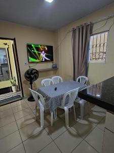 a dining room with a table and chairs and a tv at Casa de temporada 08 Pessoas PISCINA LAZER Entretenimento pra família in João Pessoa