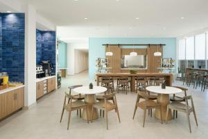 a dining room with tables and chairs and a kitchen at Element by Marriott Opelika Auburn in Opelika