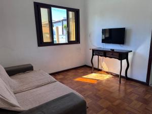 a living room with a couch and a table with a television at Casa Vila Nova Alvorada in Imbituba