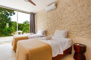 two beds in a room with a brick wall at 11BR I Hacienda Zalama in Tulum +144 photos