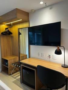 a room with a desk with a chair and a large television at Ap Tryp by Wyndham Nações in Brasília
