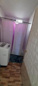 a bathroom with a toilet and a purple shower curtain at Hostal Pura Vida in Santiago +8 photos