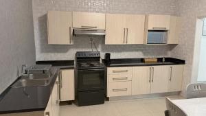 a kitchen with white cabinets and black appliances at Artem Apartments - Apartment 3 in Kitwe