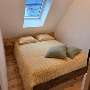 a bedroom with a bed with two pillows and a window at Maison Ty Bian Prieuré in Pleubian