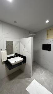 a white bathroom with a sink and a mirror at Seridó Acomodações in Caicó
