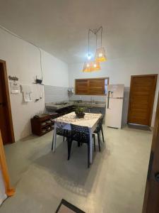 a kitchen with a table and a refrigerator at Casa Refúgio do Rio in Caraíva