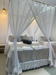 a white canopy bed with white curtains in a bedroom at Casa Refúgio do Rio in Caraíva
