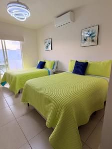 two beds in a room with green sheets at Sunset Point San Carlos in San Carlos
