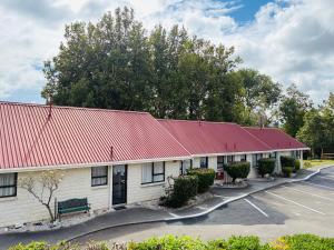 a building with a red roof and a parking lot at Awatea Park Motel in Palmerston North