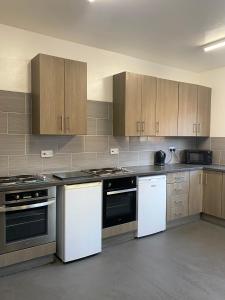 a kitchen with white appliances and wooden cabinets at Contractor House with parking in Worksop