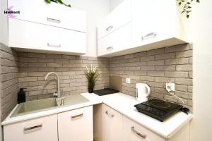 a kitchen with white cabinets and a sink at MMRent Divine Room in Gdańsk