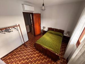 a bedroom with a bed with a green blanket at Refugio do Alto de Levira in Anadia