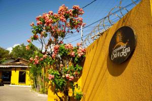 a sign on the side of a yellow wall with flowers at Pousada Sol e Luna - Pipa Garden in Pipa